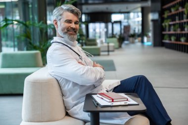 Memnun bir doktor. Laboratuvar önlüğü giymiş gülümseyen olgun erkek doktor olumlu ve memnun görünüyor.