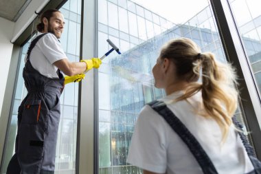 Takım çalışması. Ofis temizliği yapan ve memnun görünen gençler.