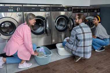 Çamaşırhanedeki insanlar ev işlerini bitirdikten sonra yeni giysiler düzenliyorlar.