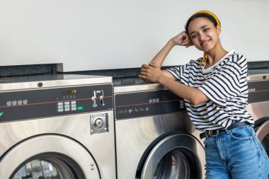 Çamaşır odasında çamaşır yıkayan bir kadın endüstriyel çamaşır makinesinde ev işlerini yapıyor.