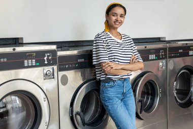 Çamaşır odasında çamaşır yıkayan bir kadın endüstriyel çamaşır makinesinde ev işlerini yapıyor.