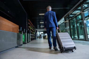 Varış yeri. Bavullu bir adam varış noktasına vardıktan sonra çıkışa gidiyor.