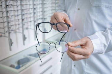 Farklı gözlükler. Optik mağazasında bir müşteriye gözlük gösteren bir gözlük asistanı