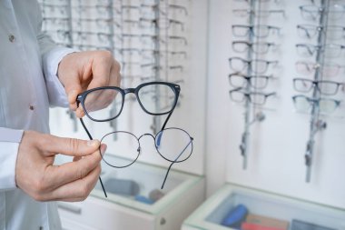 Farklı gözlükler. Optik mağazasında bir müşteriye gözlük gösteren bir gözlük asistanı