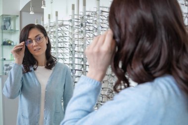 Yeni gözlük. Optik dükkanında yeni gözlük seçen kadın müşteri