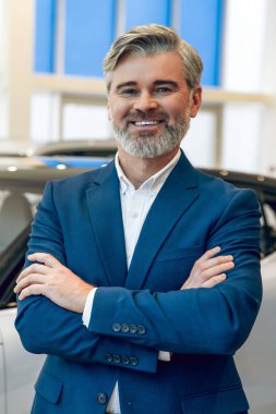 Sakallı, gülümseyen satıcı galeride araç satıyor.