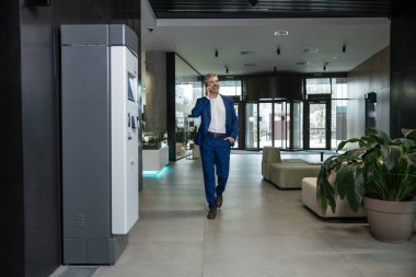 İş günü. İş adamı iş merkezinde koridorda yürüyor.