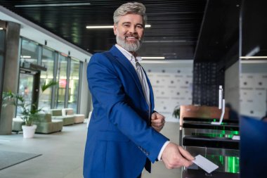 Ofise giriyorum. Koyu mavi takım elbiseli, gri saçlı, olgun bir iş adamı ofise giriş kartıyla giriyor.