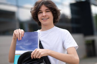 Üniversite kampüsünde eğitime hazır poz veren gülümseyen ergen.