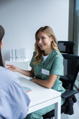 Üniformalı kadın doktor hastane ofisinde hastayla konuşuyor.