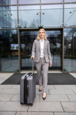 Geldik. Sarışın, uzun saçlı, şık takım elbiseli kadın havaalanı girişinde.