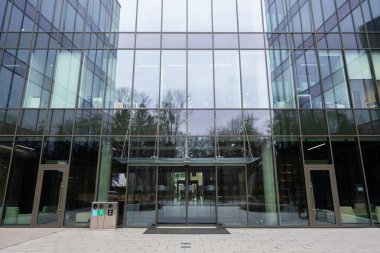 Modern mimari. Camdan duvarları olan büyük, modern bir binanın resmi.