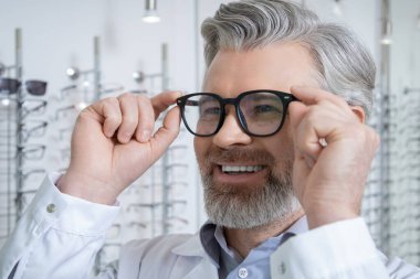 Gözlüklü adam. Yeni gözlük deneyen olgun sakallı beyaz bir adamın portresi.