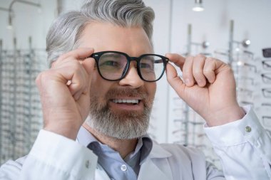 Gözlüklü adam. Yeni gözlük deneyen olgun sakallı beyaz bir adamın portresi.