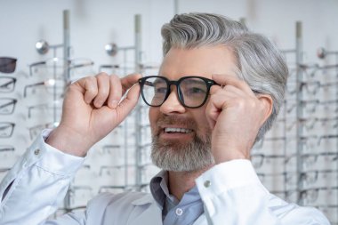 Gözlüklü adam. Yeni gözlük deneyen olgun sakallı beyaz bir adamın portresi.