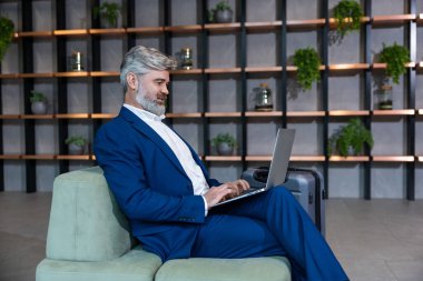 İş adamıyım. Ofisinde dizüstü bilgisayarla çalışan şık giyimli bir iş adamı.