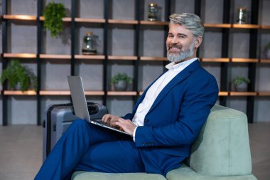 İş adamıyım. Ofisinde dizüstü bilgisayarla çalışan şık giyimli bir iş adamı.