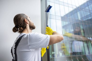 Pencere temizliği. Pencereyi temizleyen genç adam pencere temizleyicisiyle