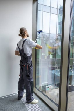 Pencere temizliği. Pencereyi temizleyen genç adam pencere temizleyicisiyle