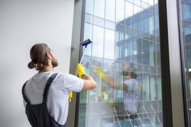 Temizlik. Genç sakallı servis elemanı ofisi temizlerken meşgul görünüyor.