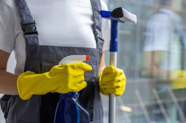 Pencereleri temizliyorum. Kadın temizlikçi elinde cam temizleyicisiyle dikiliyor.