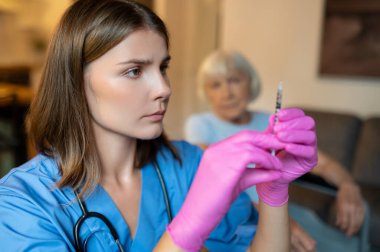 Kafkas kadın doktor klinikte yaşlı kadın hasta enjekte ediyor.