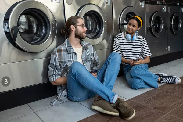 Kadın ve erkek iletişim kuruyor ve çamaşırhanede günlük işlerini birlikte yapıyorlar.