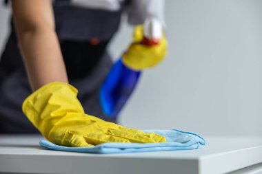 Dezenfekte. Temizlik ekibinden bir kadın masa yüzeyini dezenfekte ediyor.