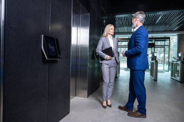 Asansörde konuşuruz. İş merkezinde asansör beklerken iki meslektaş konuşuyor.