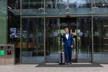 Geldik. Havalimanı girişinde zarif, olgun bir iş adamı var.