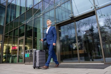 Geldik. Mavi takım elbiseli şık bir adam bir bavul taşıyor.