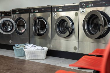 Çamaşırhanede ve kirli giysileri yakınlarda olan sepette çamaşır makineleri.