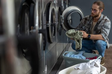 Yakışıklı adam çamaşırlarını yıkamak için kamusal alanda kaliteli para kullanıyor.