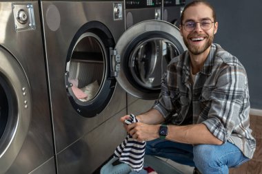 Yakışıklı adam çamaşırlarını yıkamak için kamusal alanda kaliteli para kullanıyor.