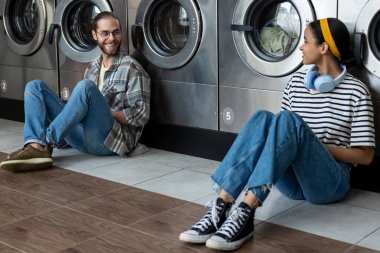 Kadın ve erkek iletişim kuruyor ve çamaşırhanede günlük işlerini birlikte yapıyorlar.