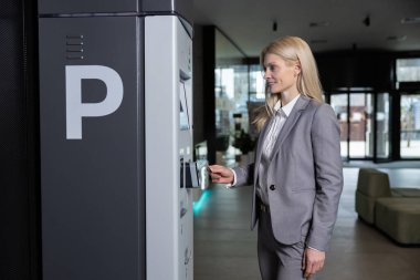 Kamu tesisinde kablosuz sisteme sahip park cezası ödemesi için makineye kartı sokan kadın