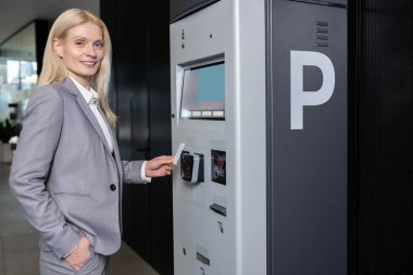 Otomotiv istasyonunda bilet almak ve yer açmak için elektronik sistem kullanan kadın.