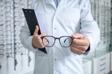 Yeni gözlük. Ellerinde gözlük olan erkek göz doktorunun resmini kapat.