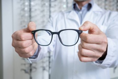 Yeni gözlük. Ellerinde gözlük olan erkek göz doktorunun resmini kapat.