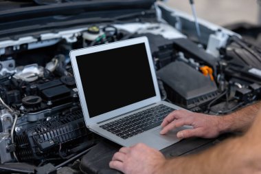 Otomotiv endüstrisindeki adam otomobil tamir servisindeki bilgisayarı kontrol ediyor.