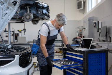 Otomotiv endüstrisindeki adam otomobil tamir servisindeki bilgisayarı kontrol ediyor.