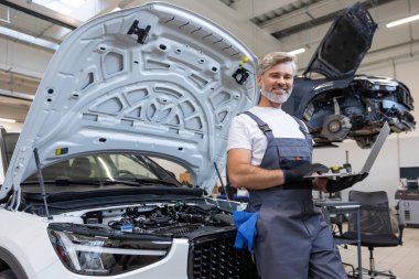 Garajdaki boncuklu tamirci, motor denetimi için dizüstü bilgisayar kullanıyor.