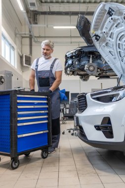 Garajda profesyonel ekipman kullanarak araba tamir eden bir tamirci var.