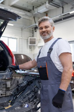 Sakallı otomotiv işçisi atölyede güvenlik için kontrol ve kontrol yapıyor.