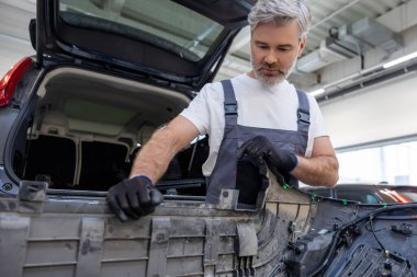 Sakallı otomotiv işçisi atölyede güvenlik için kontrol ve kontrol yapıyor.