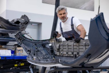 Sakallı otomotiv işçisi atölyede güvenlik için kontrol ve kontrol yapıyor.