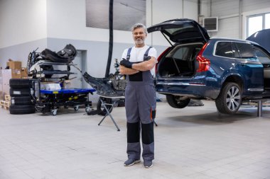 Tamirhanedeki profesyonel teknisyen aracı kontrol ediyor ve mekanik parçaları tamir ediyor.