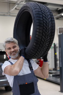 Tekerlek değiştirmek ve otomobil tamir etmek için üniforma giyen bir adam el işi yapıyor.