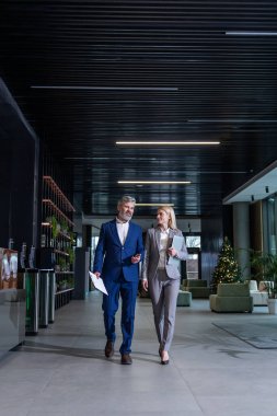 Yönetici ve çalışan koridorda dizüstü bilgisayarla takım çalışması ve iş stratejisini tartışıyor.