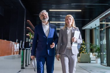 İdari işadamı ve bayan meslektaşı ofis koridorunda şirket teknolojisini tartışıyorlar.